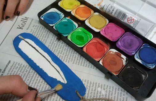 Ein Schwirrholz wird mit Tusche bemalt.