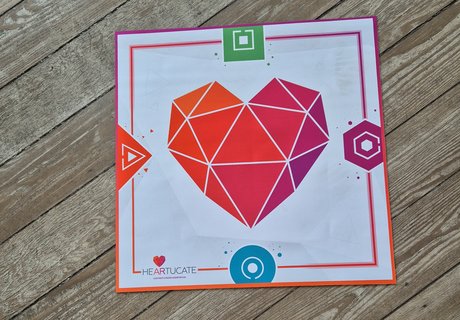 Mit einer Matte auf dem Fußboden geht es los. Die Matte trägt das Logo der Lernplattform Heartucate. Die Plattform entwickelt AR-Erlebnisse und Begleitmaterial für den Bildungsbereich. Mit Hilfe der Matte können zeitgleich vier Spielende in einen virtuellen Escape Room in der Arktis reisen.