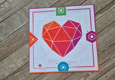 Mit einer Matte auf dem Fußboden geht es los. Die Matte trägt das Logo der Lernplattform Heartucate. Die Plattform entwickelt AR-Erlebnisse und Begleitmaterial für den Bildungsbereich. Mit Hilfe der Matte können zeitgleich vier Spielende in einen virtuellen Escape Room in der Arktis reisen.