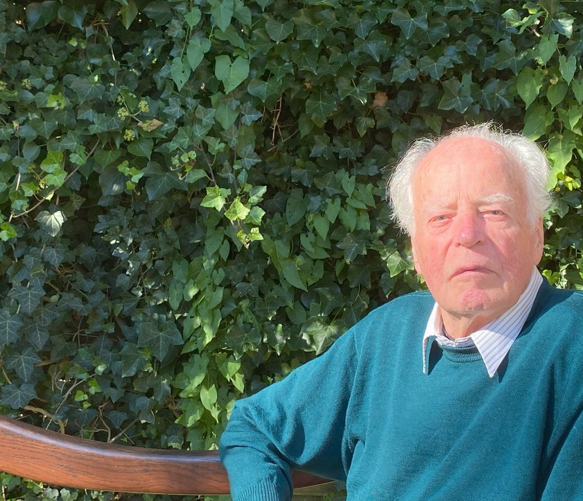 Prof. Dr. Willfried Janßen sitzt auf einer Bank im Grünen.