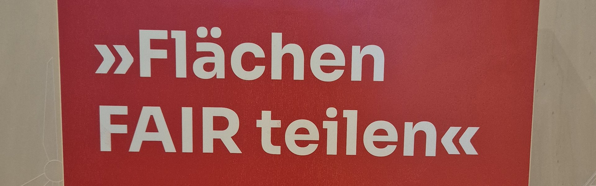 Das Foto zeigt einen Holzaufsteller mit Texttafel. Auf der Texttafel sind der Name der Wanderausstellung sowie die Gestalter als auch Sponsoren abgebildet. 