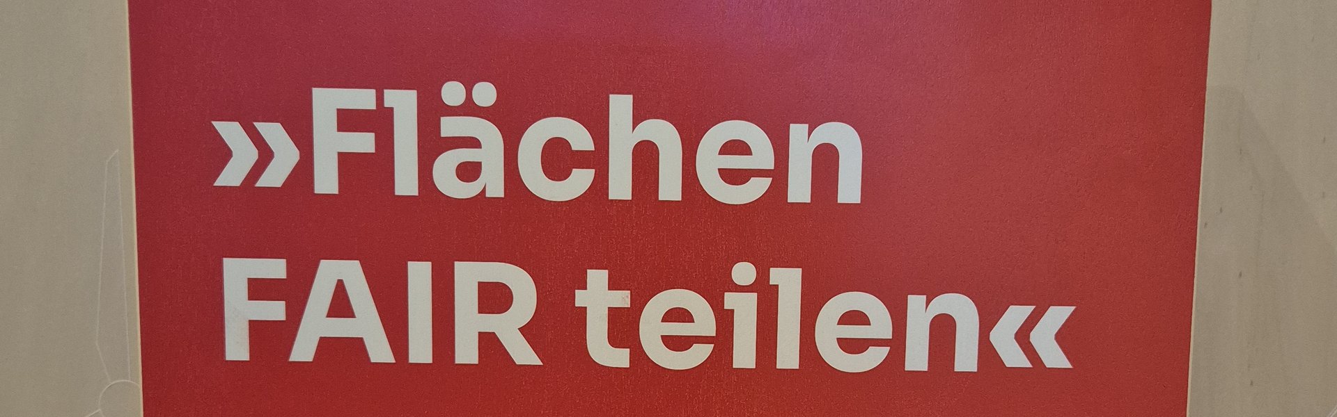 Das Foto zeigt einen Holzaufsteller mit Texttafel. Auf der Texttafel sind der Name der Wanderausstellung sowie die Gestalter als auch Sponsoren abgebildet. 