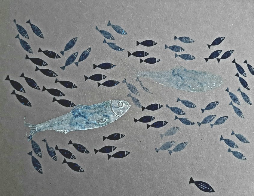 Auf dem Foto sind große und kleine Fische auf grauen Karton zu sehen. Die Fische wurden in verschiedenen Blau- und Silbertönen gestempelt. Sie schwimmen alle in die gleiche Richtung. 